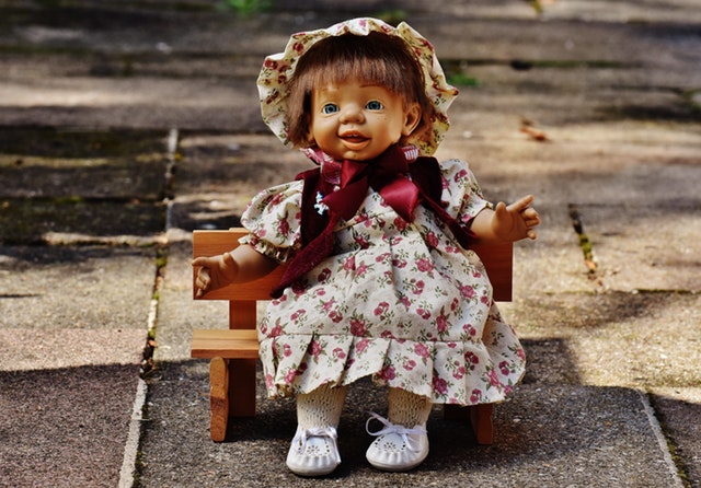 Panenka sedící na malé dřevěné lavičce